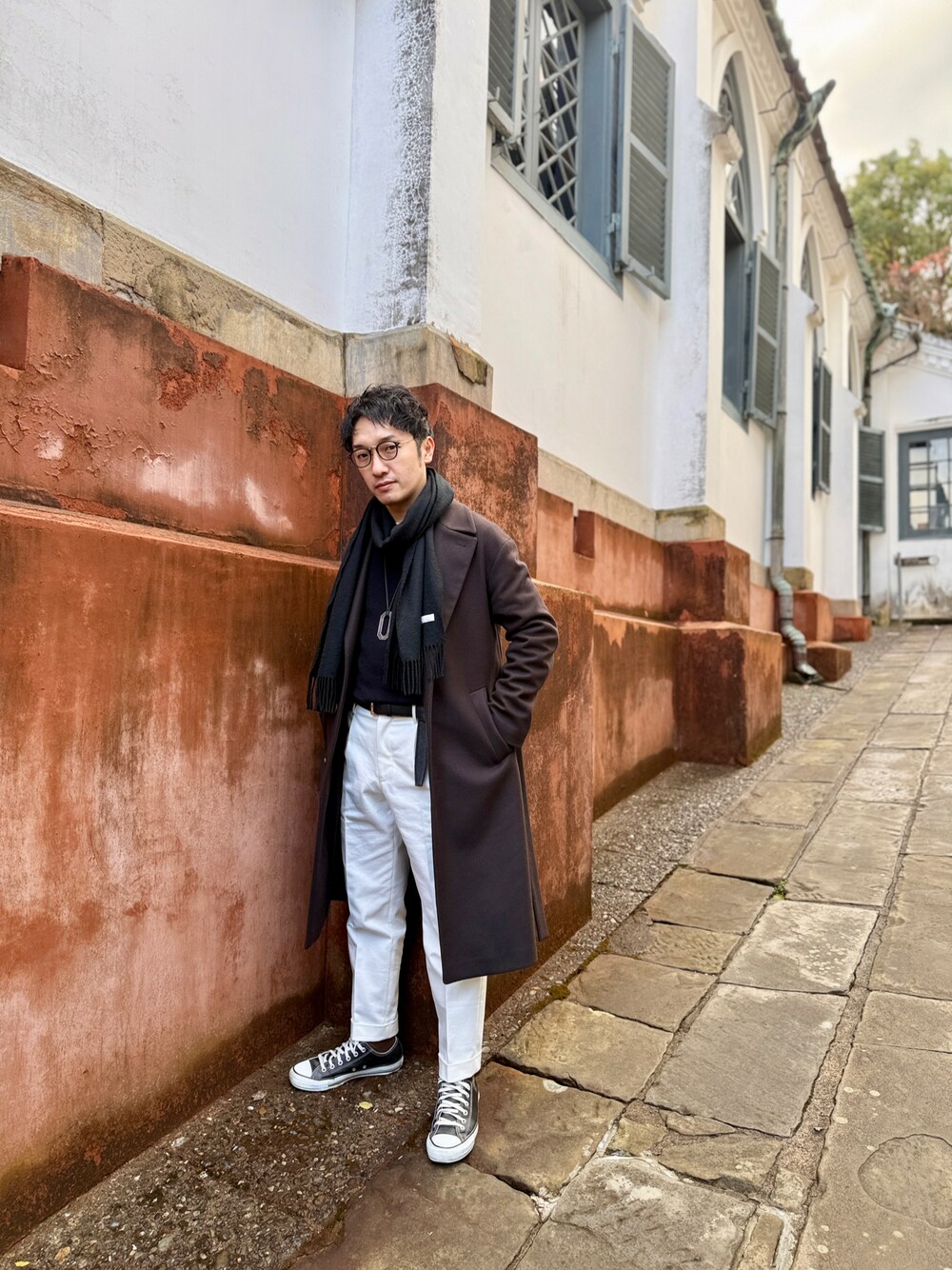 ブラウン系のジャケット/アウター、ホワイト系のスラックス、ブラック系のスニーカーを着用したメンズの冬コーディネートの1枚目の写真