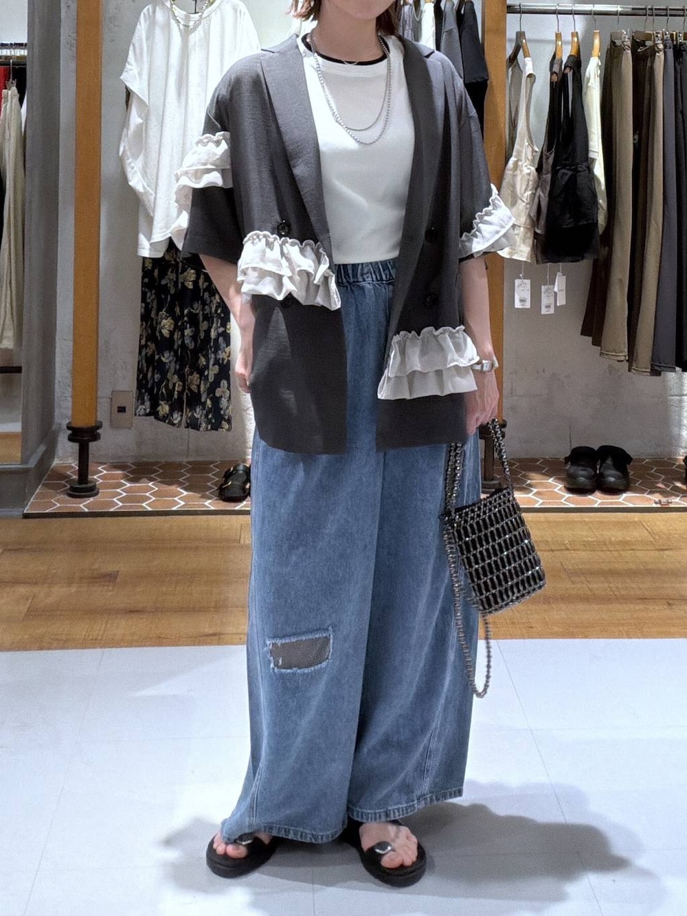 ブルー系のデニムパンツ、ブラック系のサンダル、その他のショルダーバッグを着用したレディースの夏コーディネートの1枚目の写真