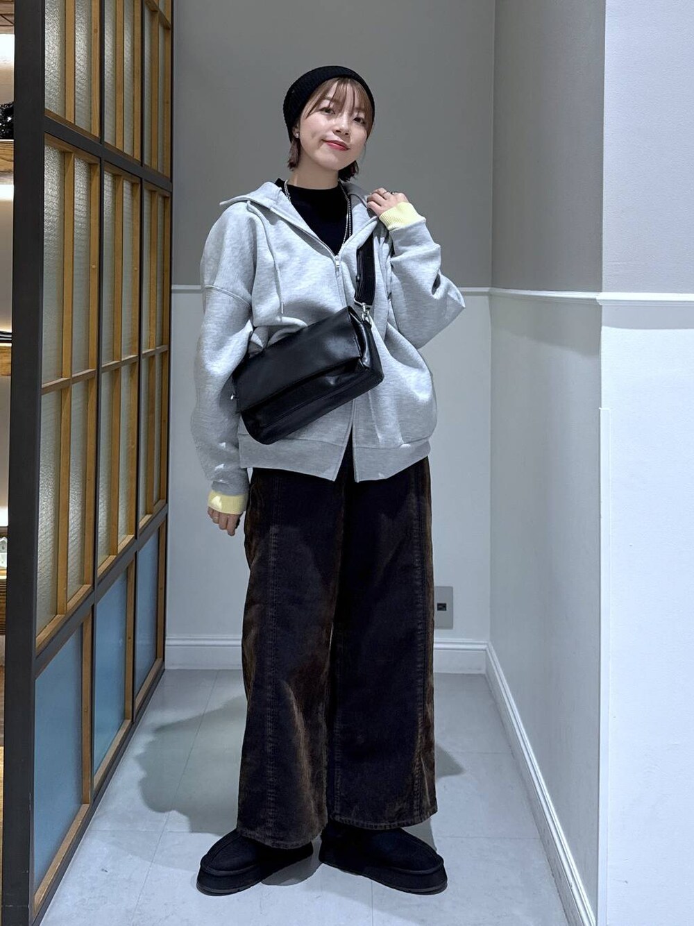ブラック系のニット/セーター、ブラック系のショルダーバッグ、グレー系のパーカーを着用したレディースの冬コーディネートの1枚目の写真