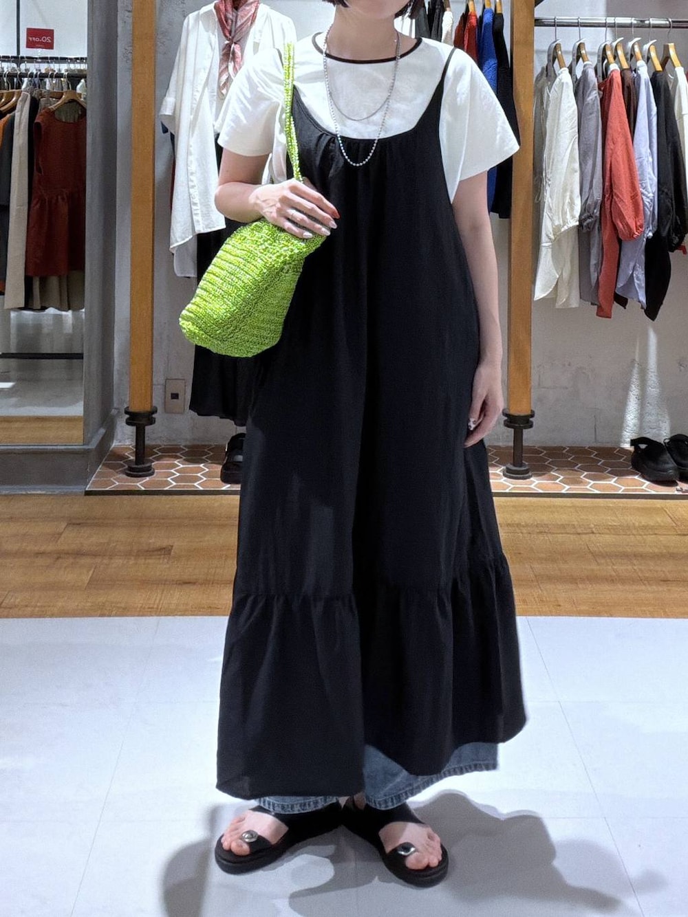 ブルー系のデニムパンツ、ブラック系のサンダル、グリーン系のショルダーバッグを着用したレディースの夏コーディネートの1枚目の写真