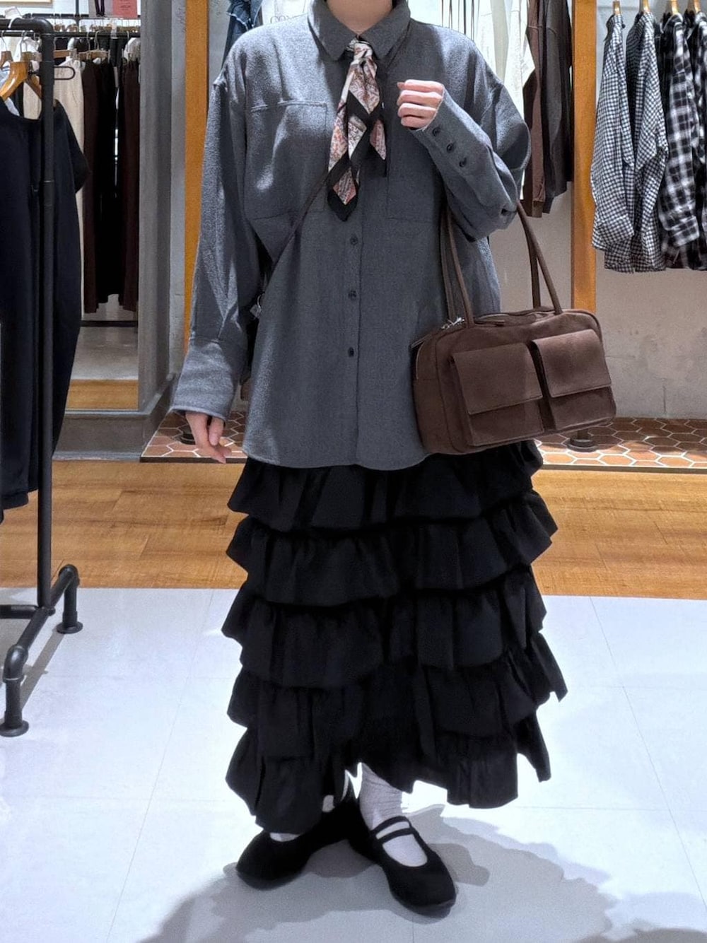 ブラック系のパンプス、ブラック系のスカート、ブラウン系のボストンバッグを着用したレディースの秋コーディネートの1枚目の写真
