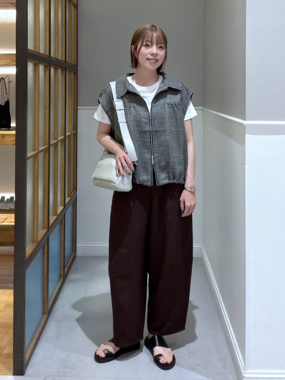 グレー系のショルダーバッグ、ブラック系のサンダル、ブラウン系のその他パンツを着用したレディースの春コーディネートの1枚目の写真