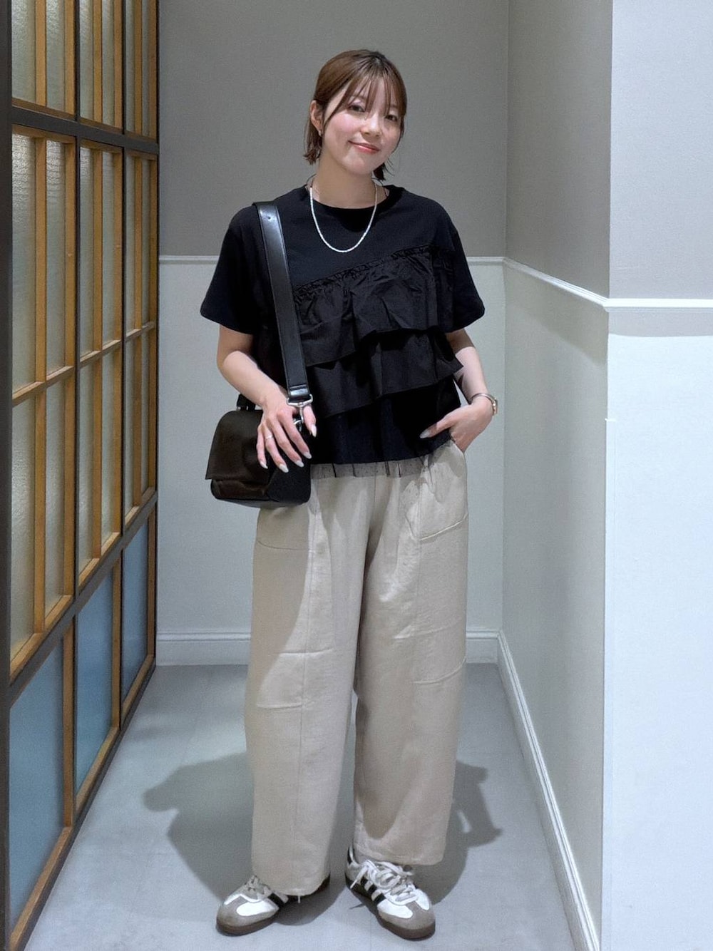 ブラック系のショルダーバッグ、ベージュ系のその他パンツ、ブラック系のTシャツ/カットソーを着用したレディースの春コーディネートの1枚目の写真