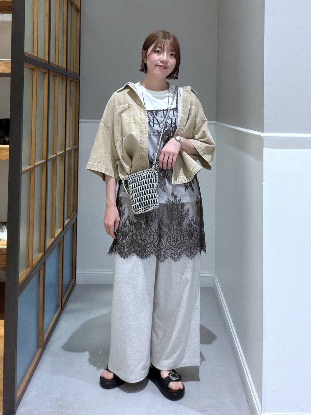 ブラック系のサンダル、ベージュ系のシャツ/ブラウス、シルバー系のショルダーバッグを着用したレディースの春コーディネートの1枚目の写真
