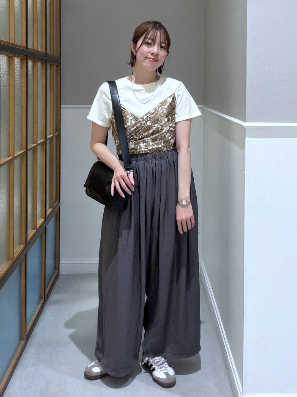 ブラック系のショルダーバッグ、グレー系のその他パンツ、ホワイト系のTシャツ/カットソーを着用したレディースの春コーディネートの1枚目の写真