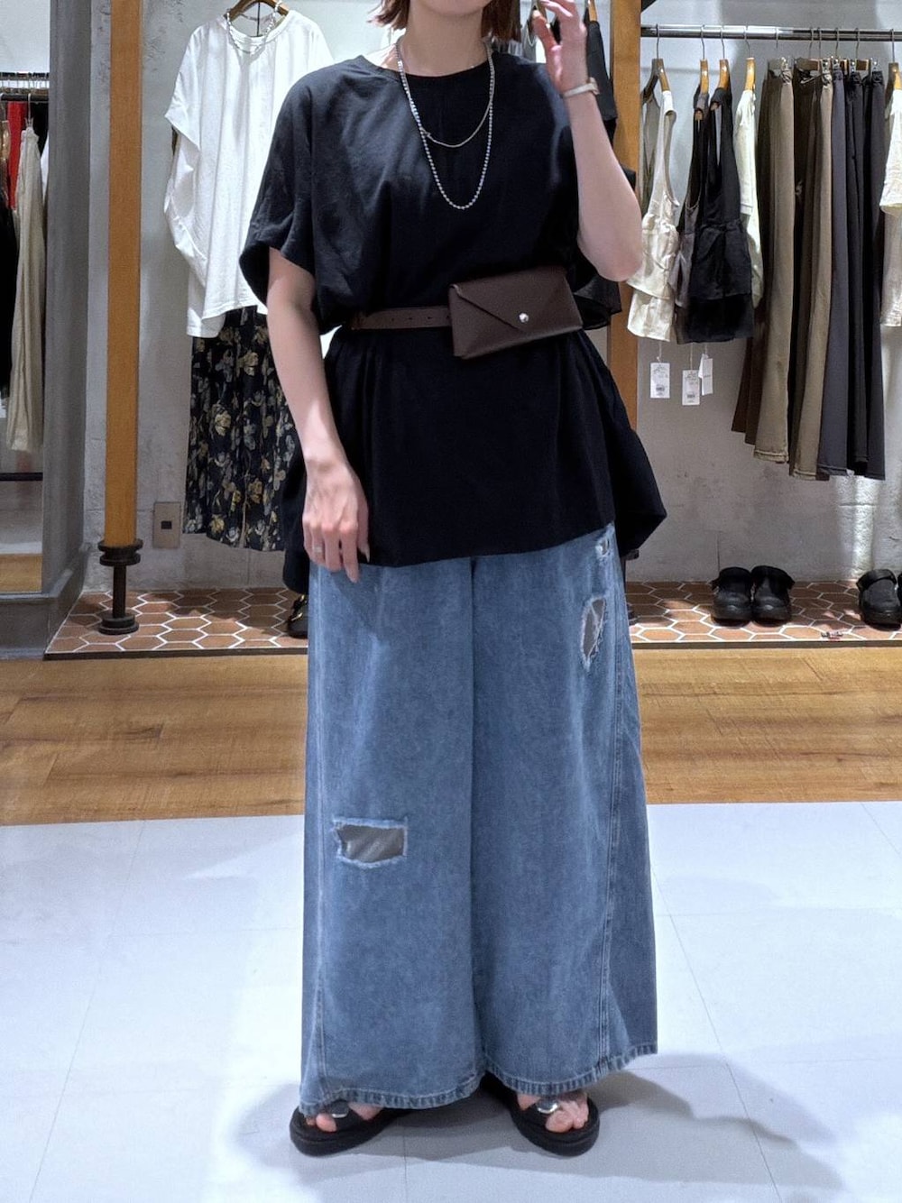 ブラック系のサンダル、ブラック系のTシャツ/カットソー、ブルー系のデニムパンツを着用したレディースの夏コーディネートの1枚目の写真