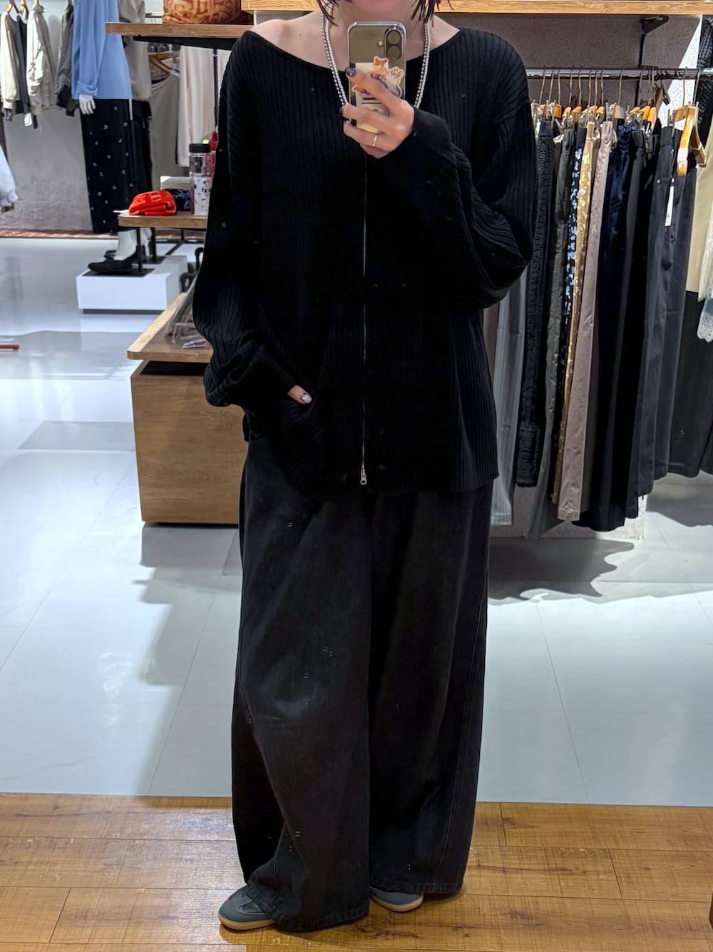 ブラック系のデニムパンツ、ブラック系のカーディガン/ボレロ、シルバー系のネックレスを着用したレディースの秋コーディネートの1枚目の写真