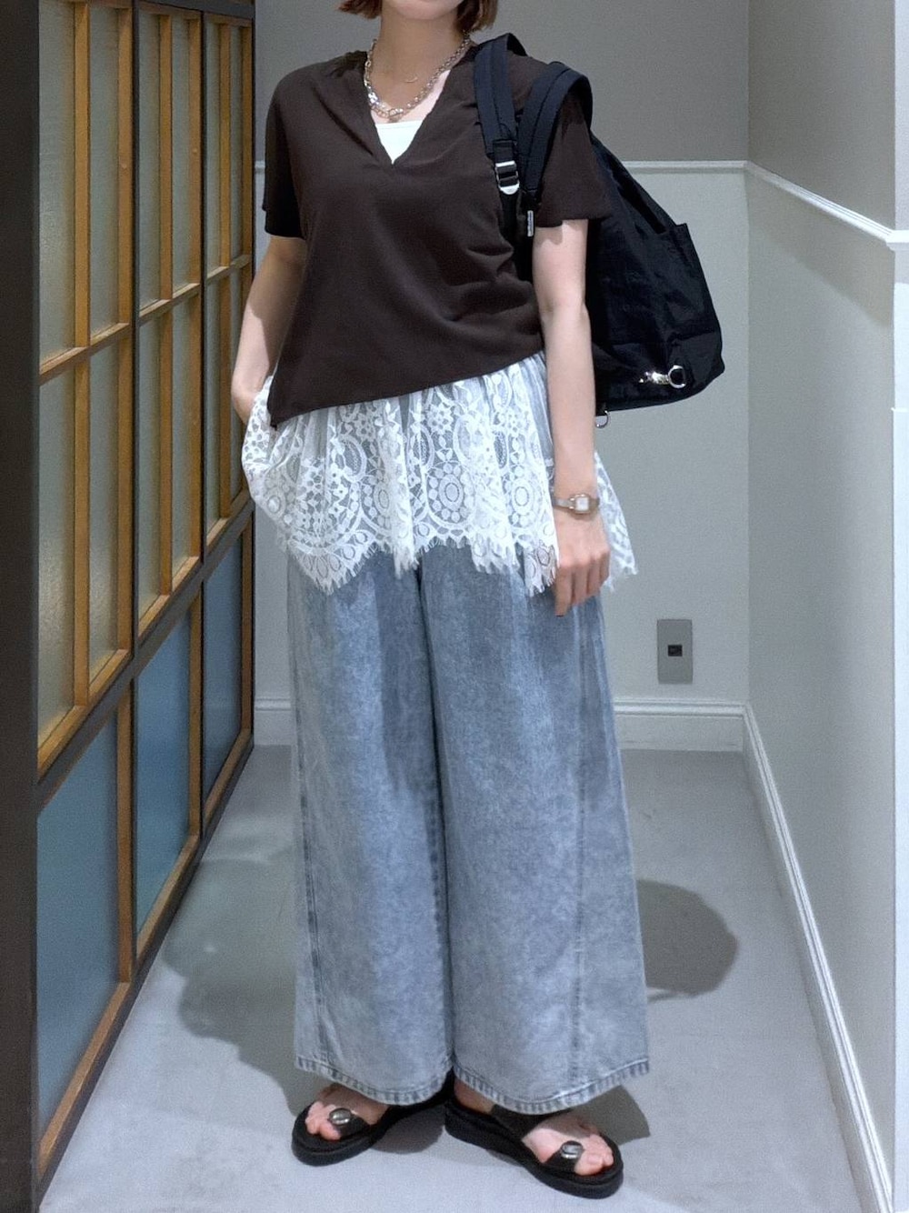 ブルー系のデニムパンツ、ブラック系のサンダル、ブラック系のバックパック/リュックを着用したレディースの春コーディネートの1枚目の写真