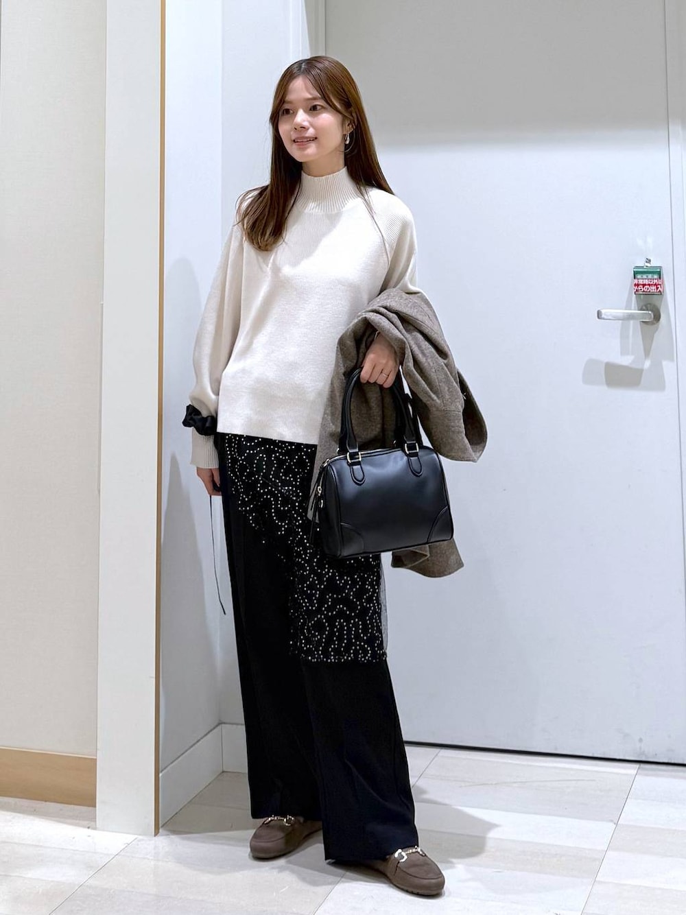ブラウン系のチェスターコート、ブラック系のその他パンツ、ホワイト系のニット/セーターを着用したレディースの秋コーディネートの1枚目の写真