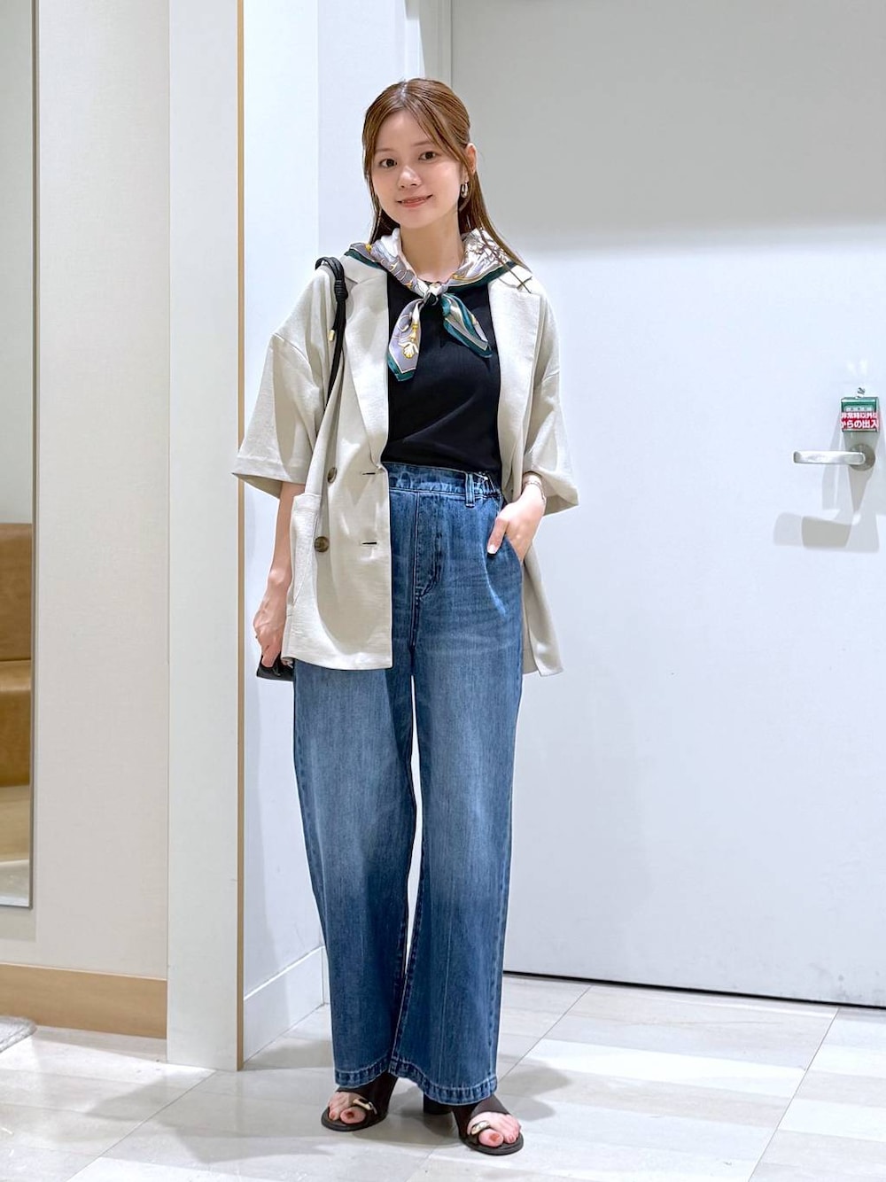 ブルー系のデニムパンツ、ブラック系のショルダーバッグ、ベージュ系のテーラードジャケットを着用したレディースの夏コーディネートの1枚目の写真