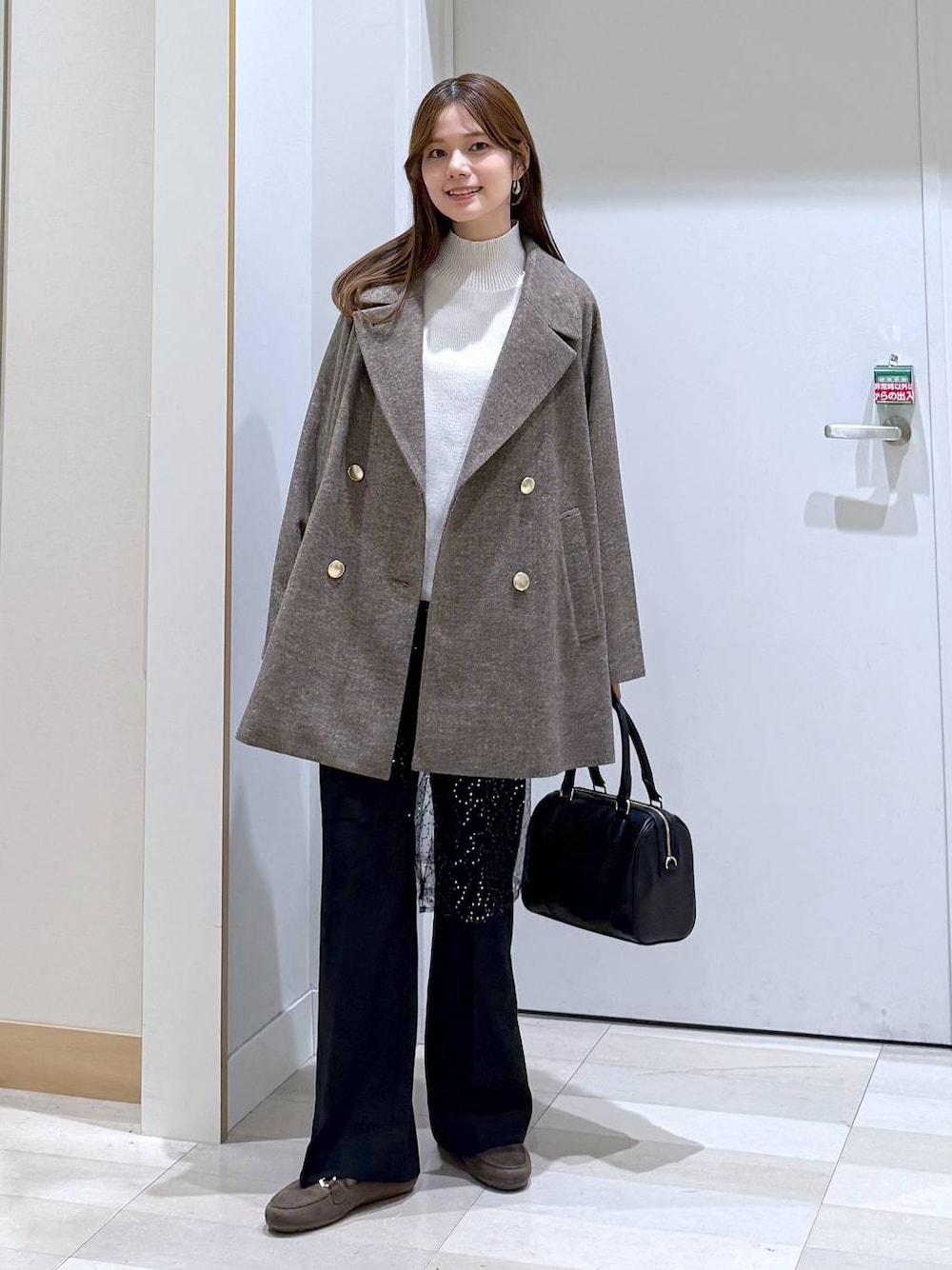 ブラウン系のチェスターコート、ブラック系のその他パンツ、ホワイト系のニット/セーターを着用したレディースの秋コーディネートの1枚目の写真