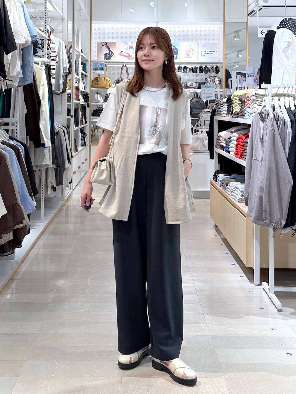 ベージュ系のショルダーバッグ、ベージュ系のベスト、ホワイト系のTシャツ/カットソーを着用したレディースの春コーディネートの1枚目の写真