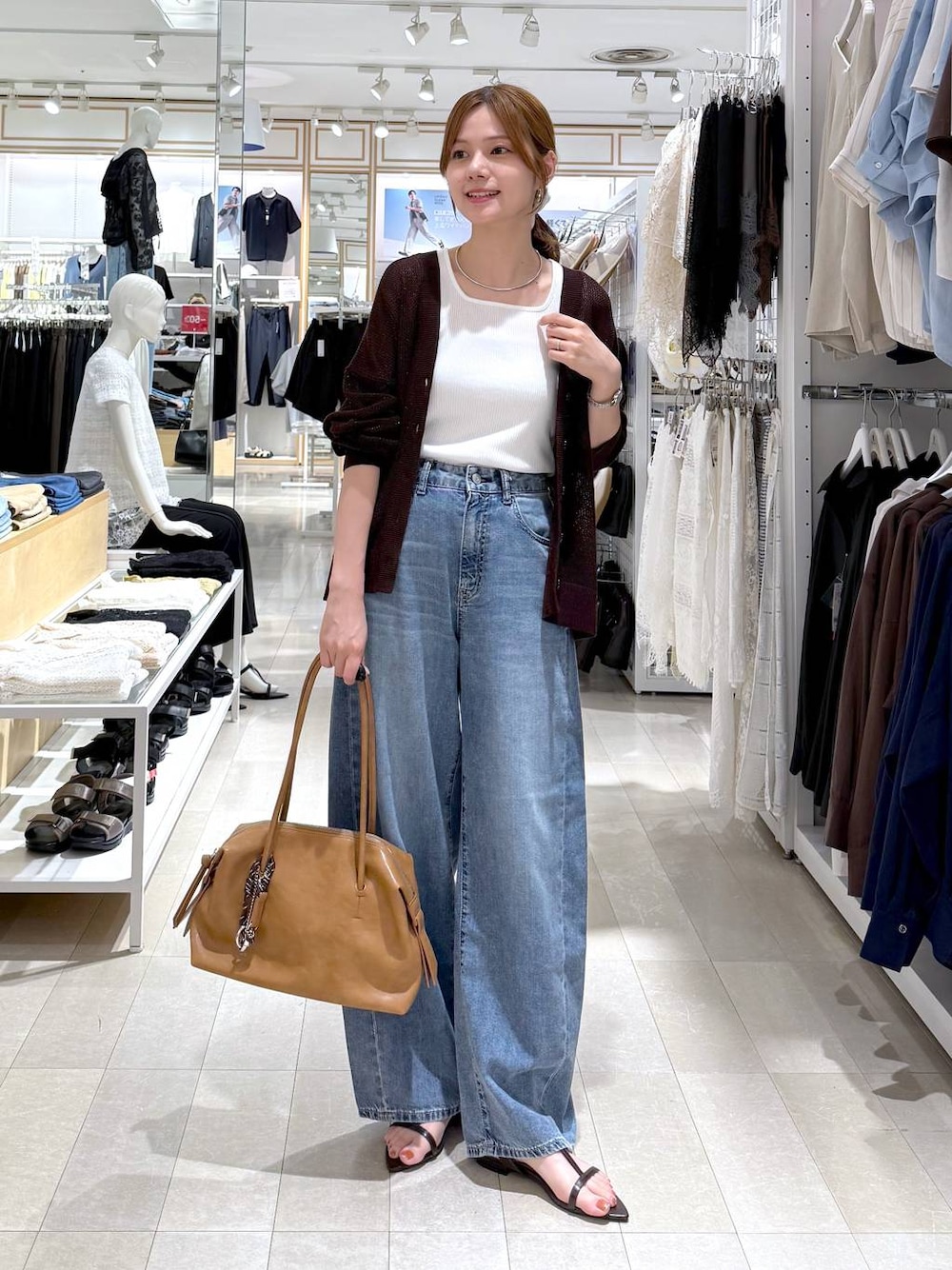 ブラウン系のボストンバッグ、ブルー系のデニムパンツ、ホワイト系のタンクトップを着用したレディースの夏コーディネートの1枚目の写真