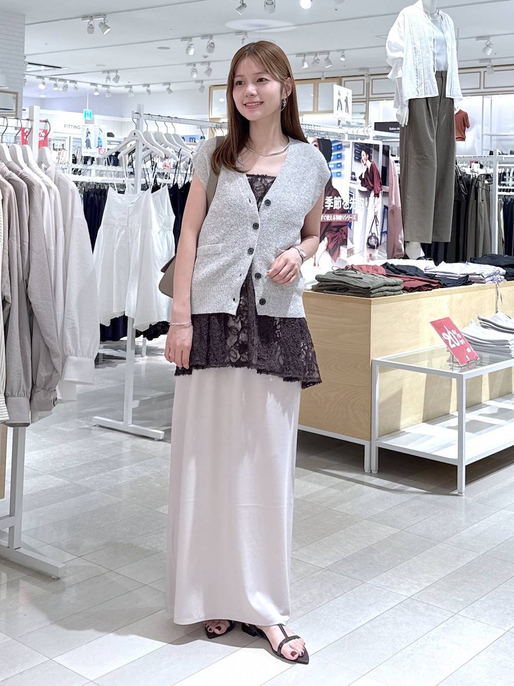 ホワイト系のスカート、ベージュ系のベスト、ブラウン系のサンダルを着用したレディースの夏コーディネートの1枚目の写真