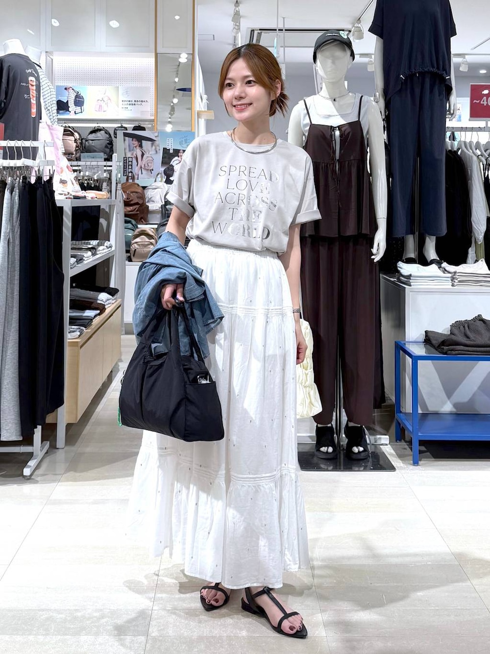 ブラック系のトートバッグ、ホワイト系のスカート、ベージュ系のTシャツ/カットソーを着用したレディースの夏コーディネートの1枚目の写真