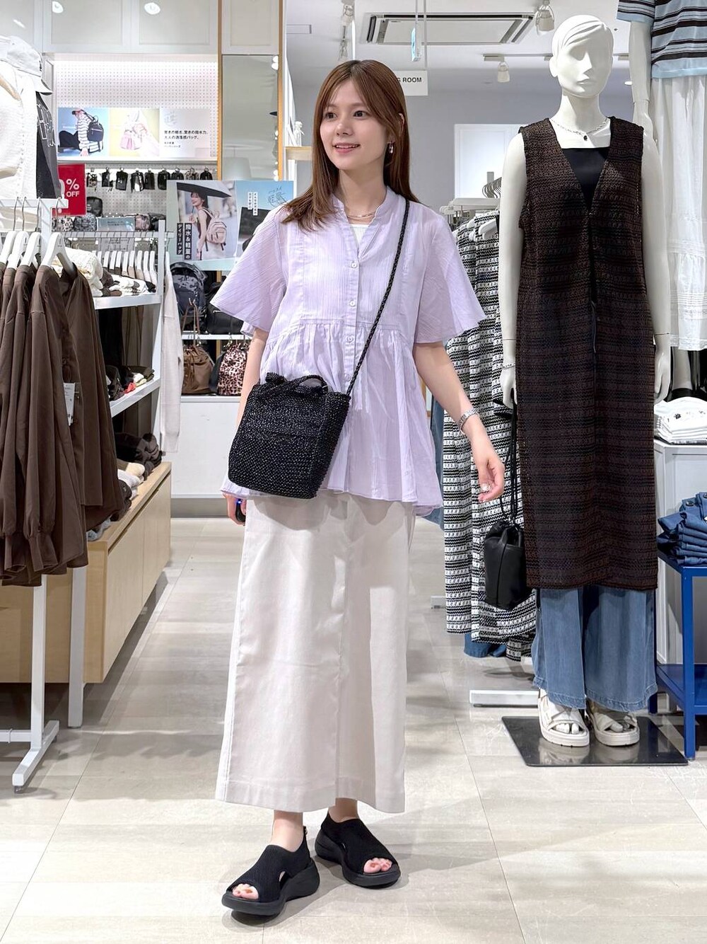 ベージュ系のスカート、ホワイト系のタンクトップ、ブラック系のクラッチバッグを着用したレディースの夏コーディネートの1枚目の写真