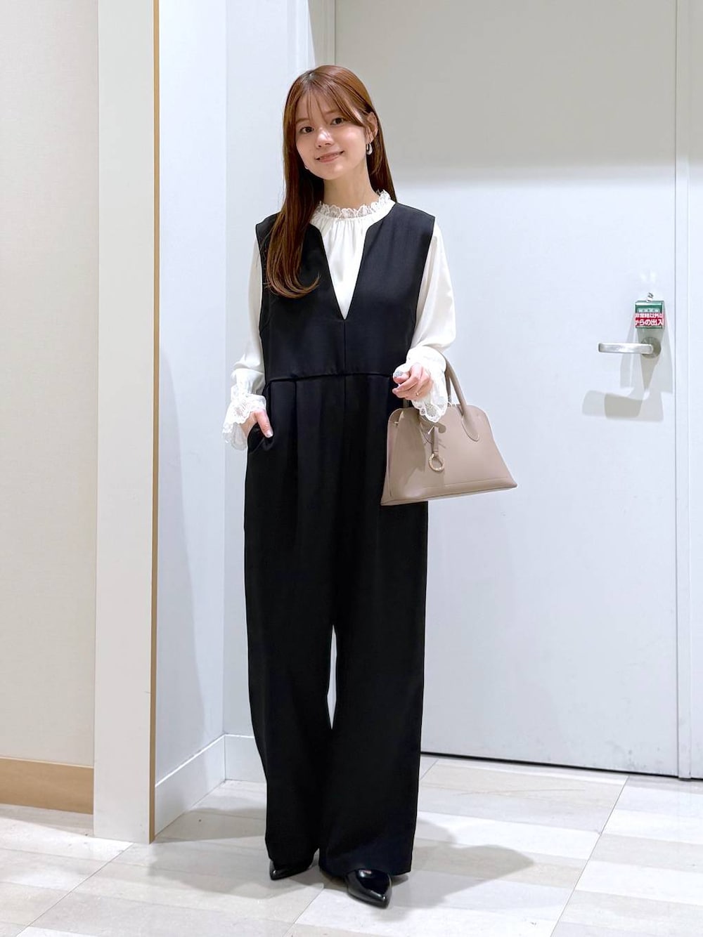 ベージュ系のショルダーバッグ、ブラック系のパンプス、ホワイト系のシャツ/ブラウスを着用したレディースの冬コーディネートの1枚目の写真