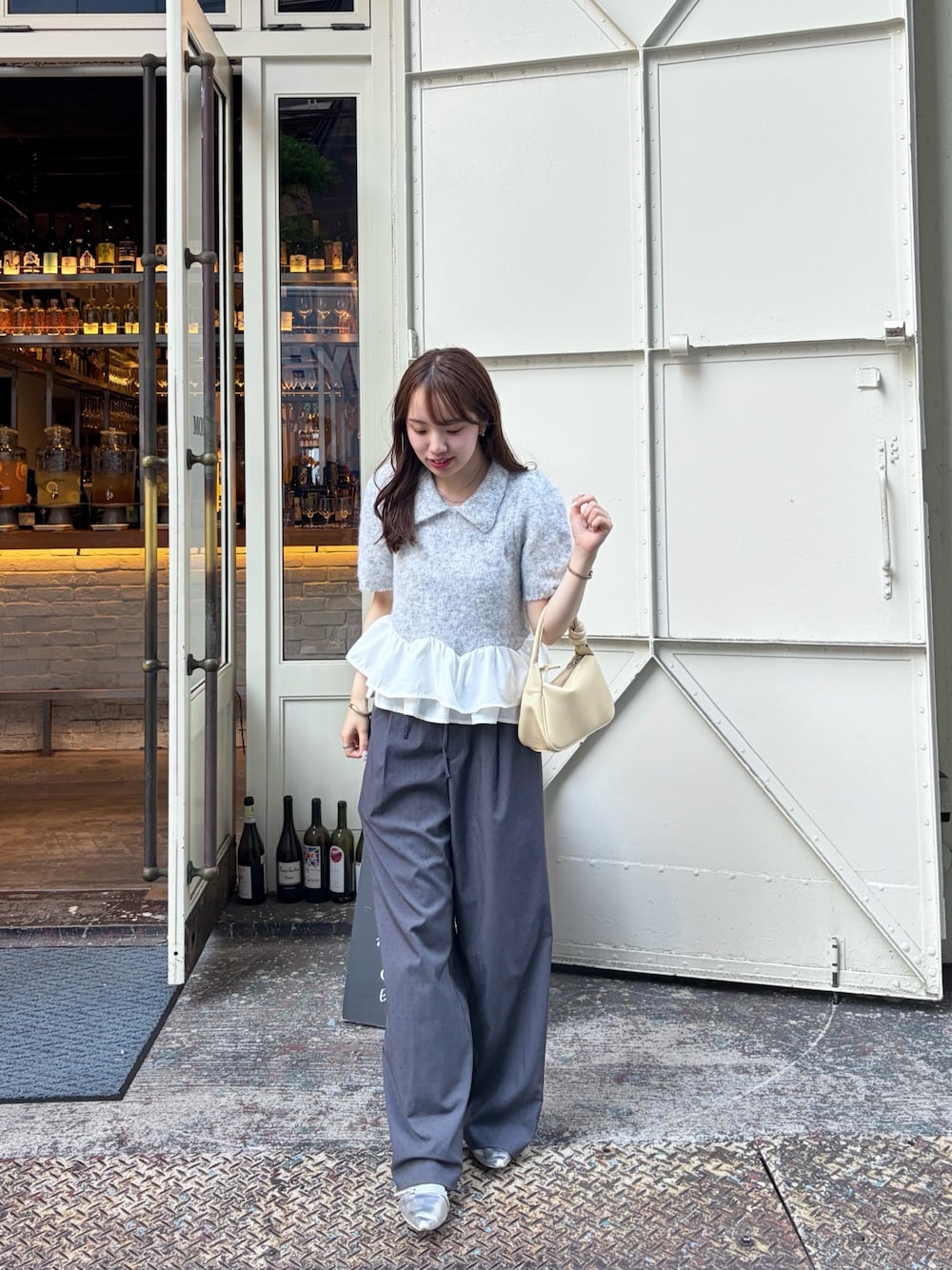 グレー系のニット/セーター、グレー系のスラックス、シルバー系のパンプスを着用したレディースの秋コーディネートの1枚目の写真