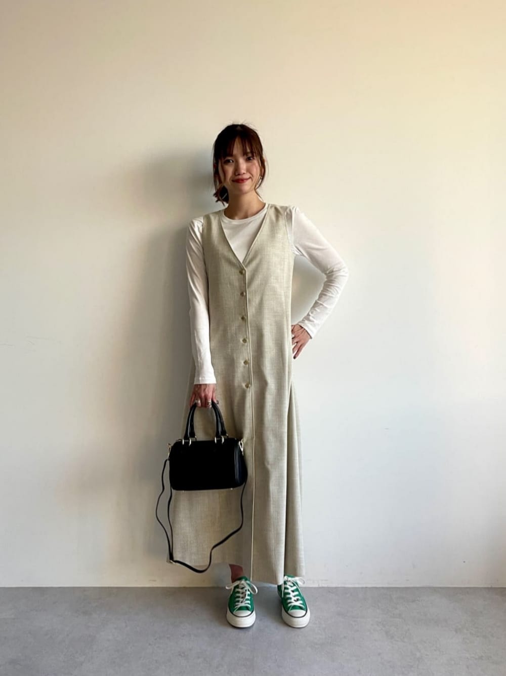 ブラック系のボストンバッグ、ホワイト系のTシャツ/カットソー、ベージュ系のジャンパースカートを着用したレディースの春コーディネートの1枚目の写真