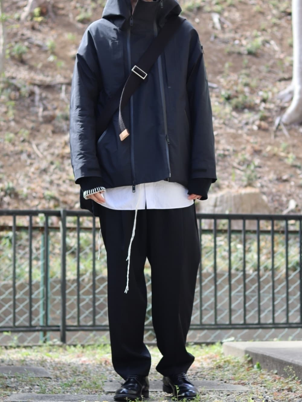 ブラック系のスラックス、ブラック系のドレスシューズ、ホワイト系のシャツ/ブラウスを着用したメンズの冬コーディネートの1枚目の写真