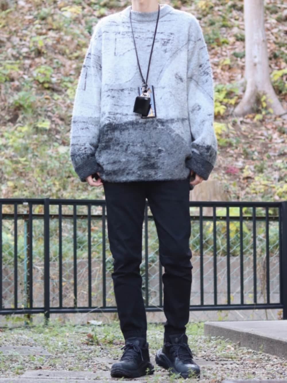 ブラック系のデニムパンツ、グレー系のニット/セーター、ブラック系のスニーカーを着用したメンズの冬コーディネートの1枚目の写真