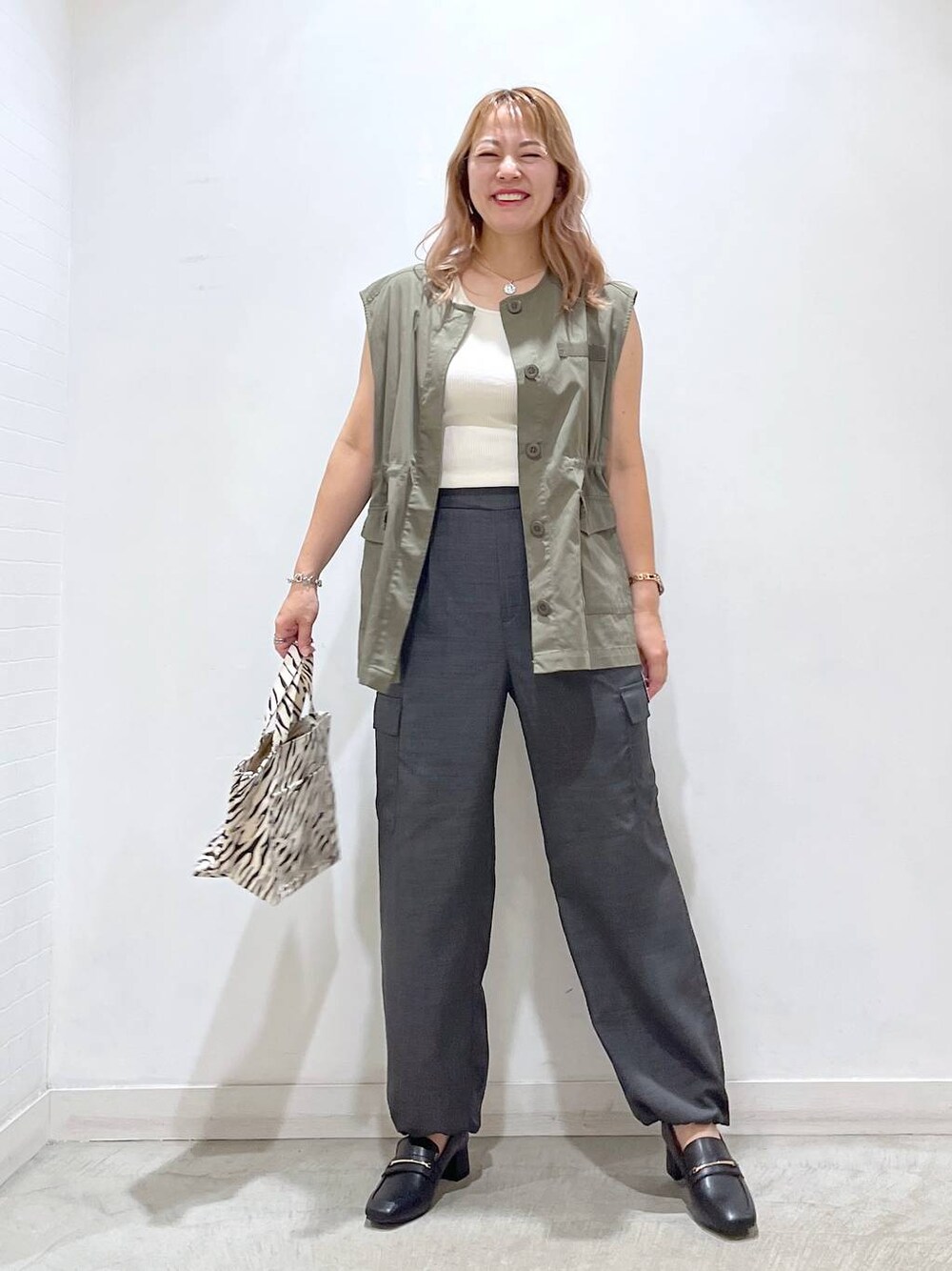 ホワイト系のタンクトップ、ブラック系のローファー、グレー系のカーゴパンツを着用したレディースの夏コーディネートの1枚目の写真