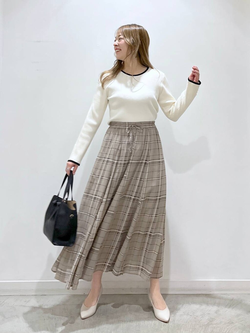 ホワイト系のTシャツ/カットソー、ホワイト系のパンプス、ブラック系のショルダーバッグを着用したレディースの春コーディネートの1枚目の写真