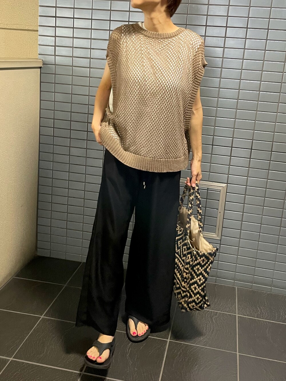 ブラック系のサンダル、ブラウン系のベスト、ブラック系のその他パンツを着用したレディースの秋コーディネートの1枚目の写真