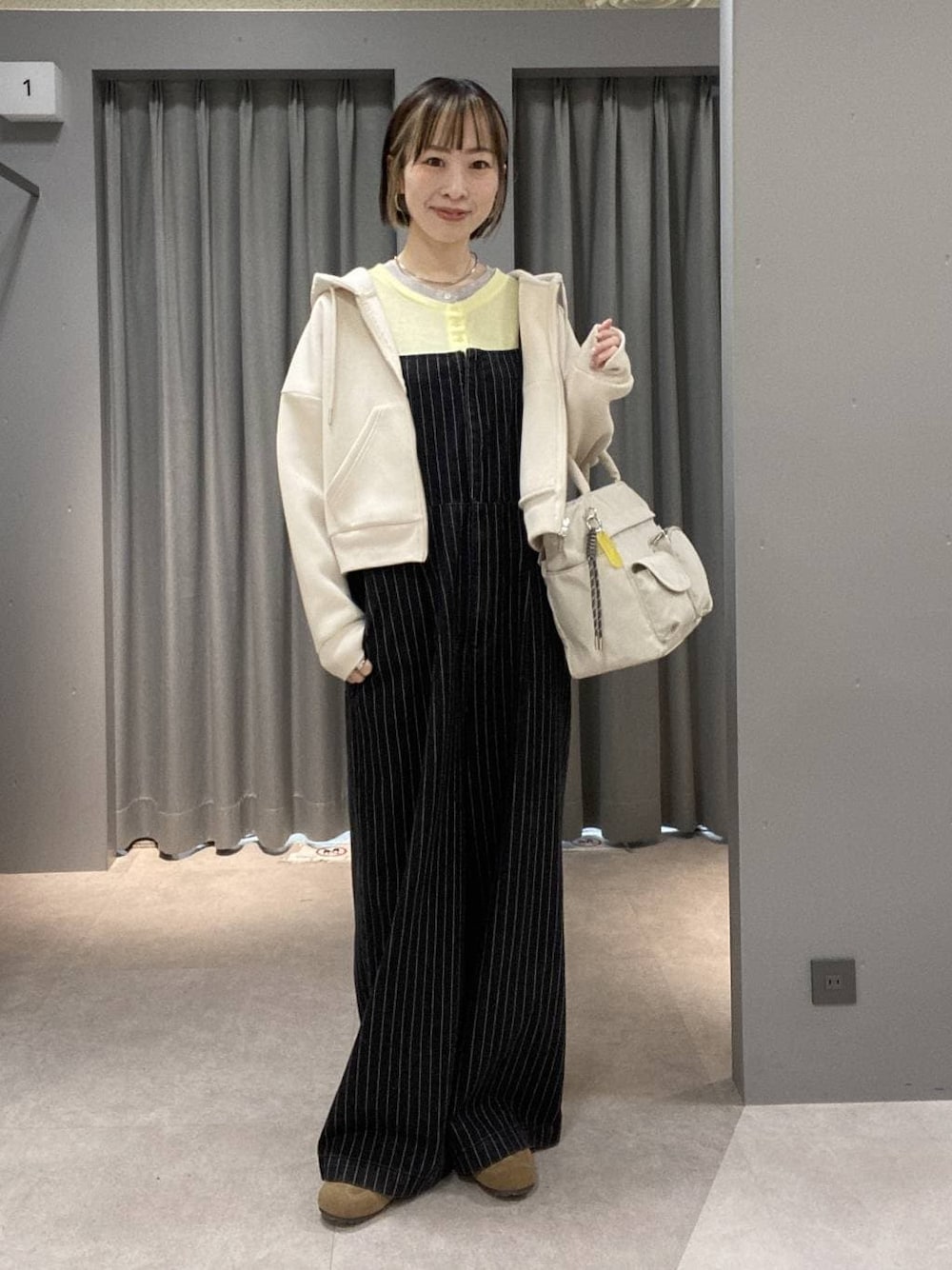 イエロー系のTシャツ/カットソー、ブラック系のサロペット/オーバーオール、ホワイト系のトートバッグを着用したレディースの冬コーディネートの1枚目の写真