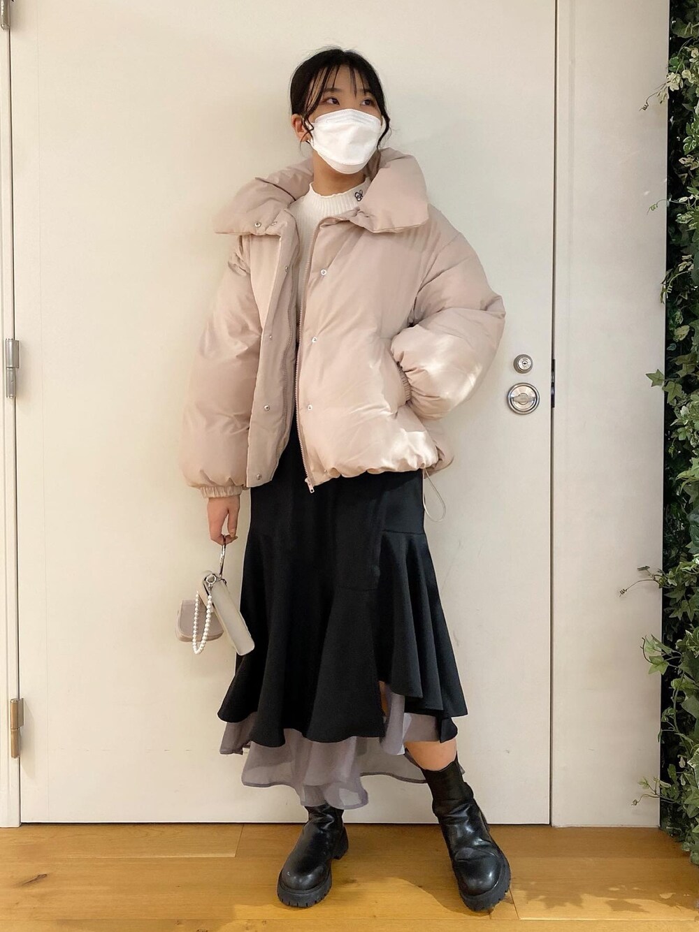 ホワイト系のニット/セーター、ピンク系のダウンジャケット/コート、ブラック系のスカートを着用したレディースの冬コーディネートの1枚目の写真