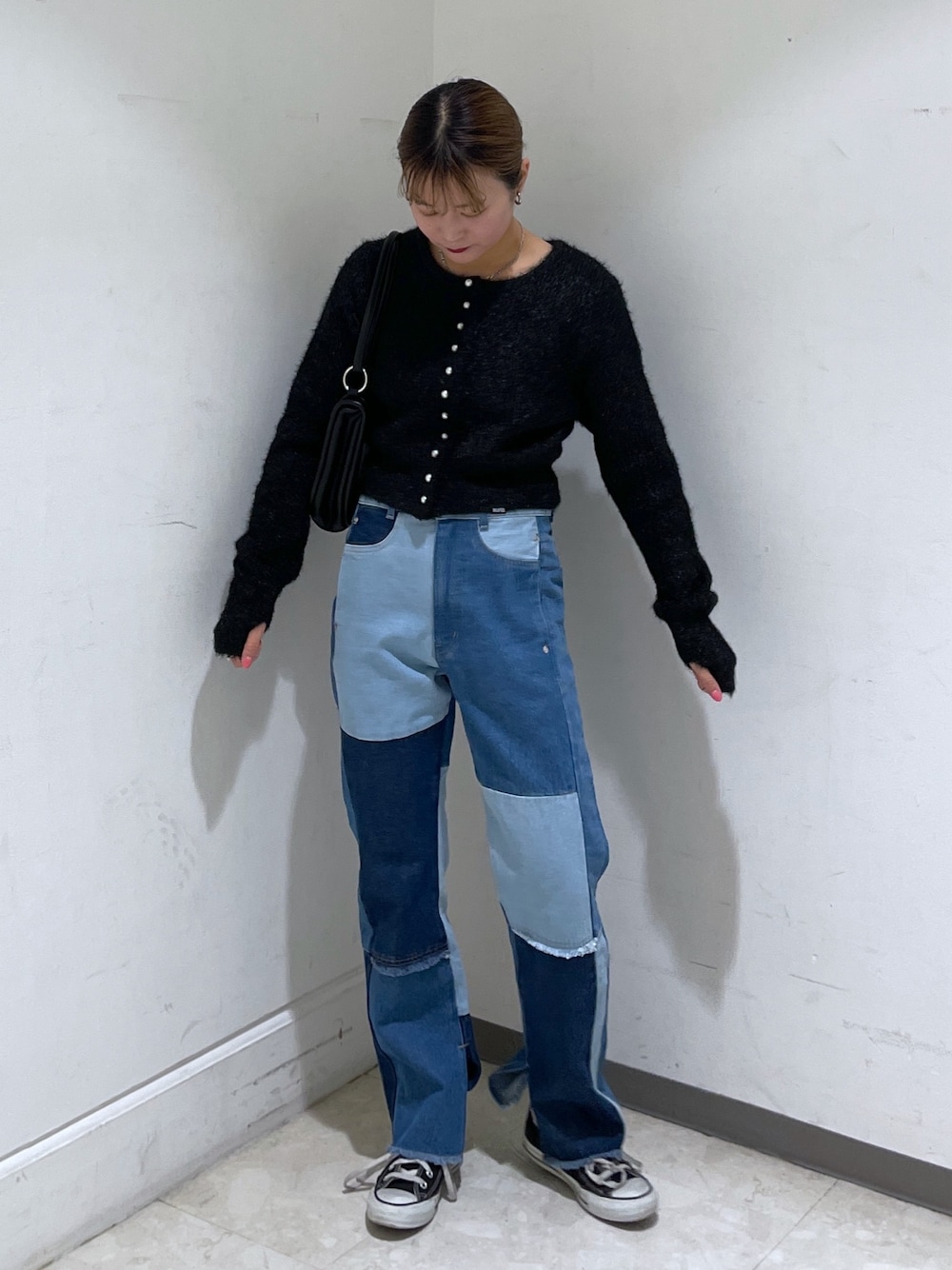 ブルー系のデニムパンツ、ブラック系のカーディガン/ボレロ、ブラック系のショルダーバッグを着用したレディースの冬コーディネートの1枚目の写真