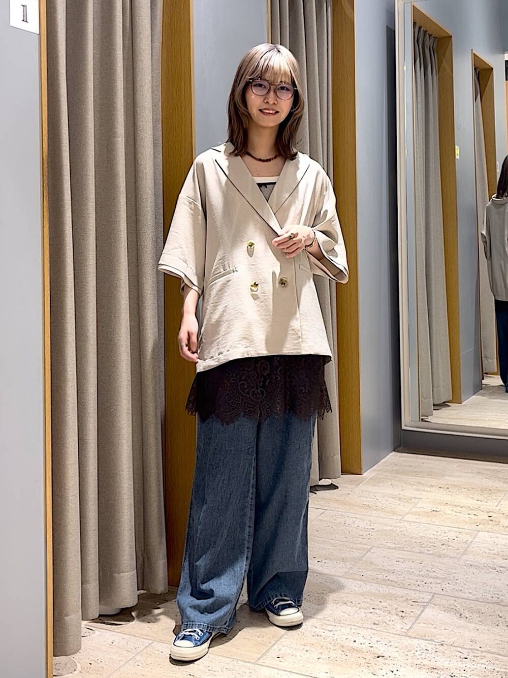 ブルー系のスニーカー、ブルー系のデニムパンツ、ベージュ系のテーラードジャケットを着用したレディースの春コーディネートの1枚目の写真