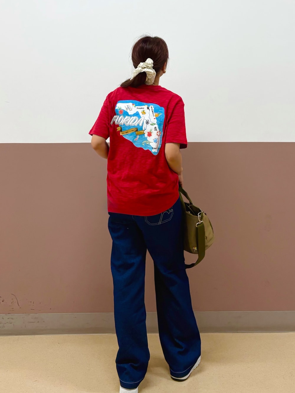 レッド系のTシャツ/カットソー、ブルー系のデニムパンツ、グリーン系のショルダーバッグを着用したレディースの夏コーディネートの1枚目の写真