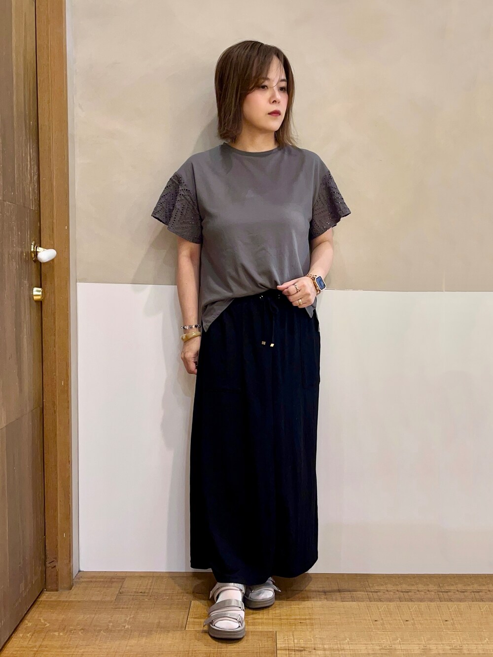 グレー系のTシャツ/カットソー、ブラック系のスカート、ブラウン系のサンダルを着用したレディースの夏コーディネートの1枚目の写真