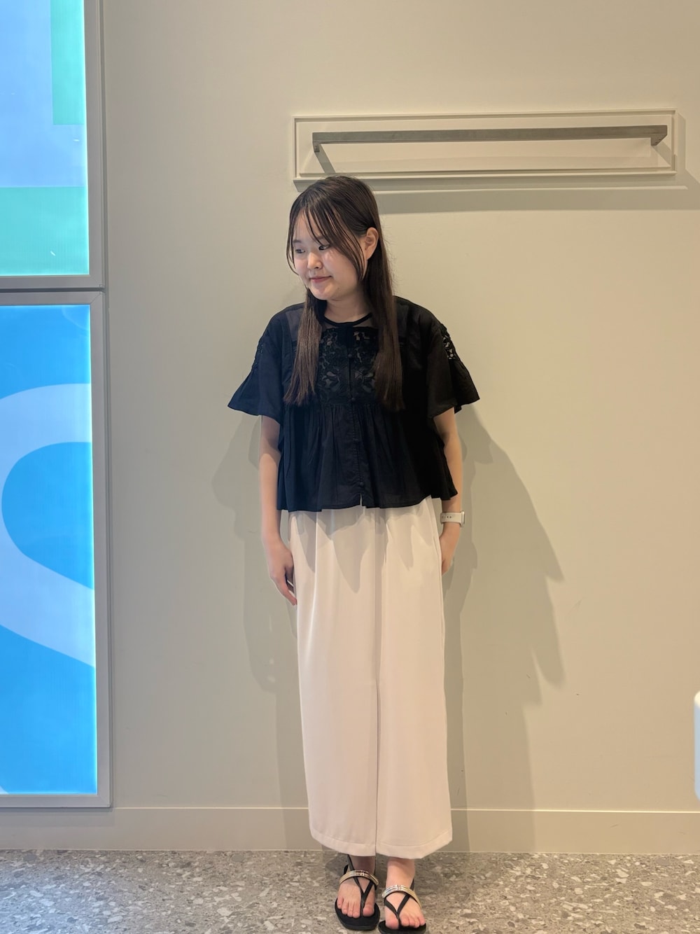 ブラック系のシャツ/ブラウス、ベージュ系のスカート、ブラック系のサンダルを着用したレディースの夏コーディネートの1枚目の写真