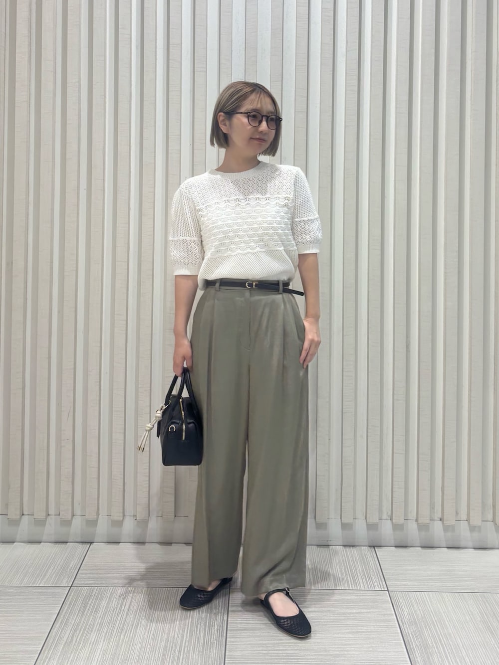 グリーン系のその他パンツ、ホワイト系のニット/セーター、ブラック系のボストンバッグを着用したレディースの夏コーディネートの1枚目の写真
