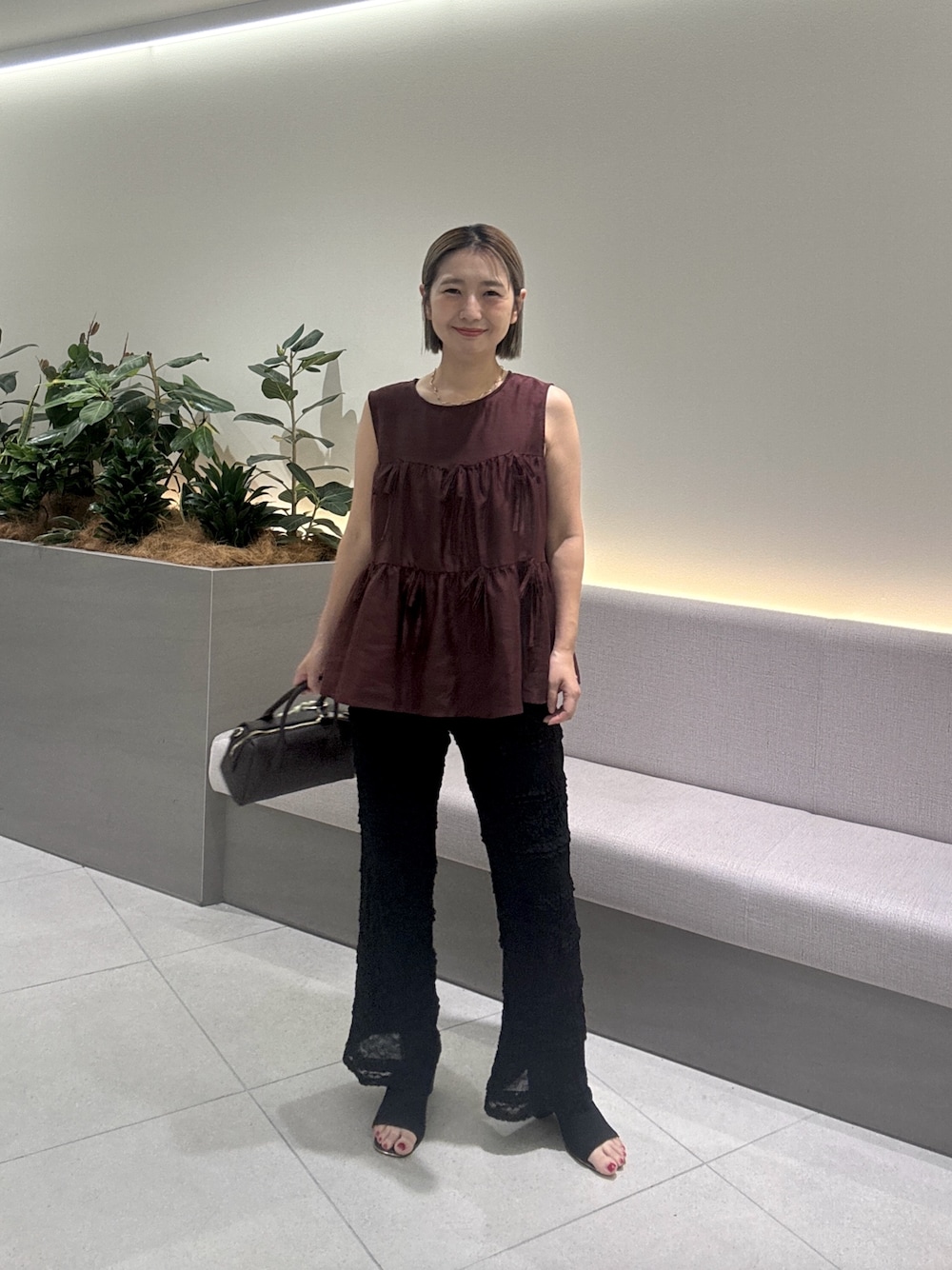 レッド系のシャツ/ブラウス、ブラック系のその他パンツ、ブラウン系のボストンバッグを着用したレディースの夏コーディネートの1枚目の写真
