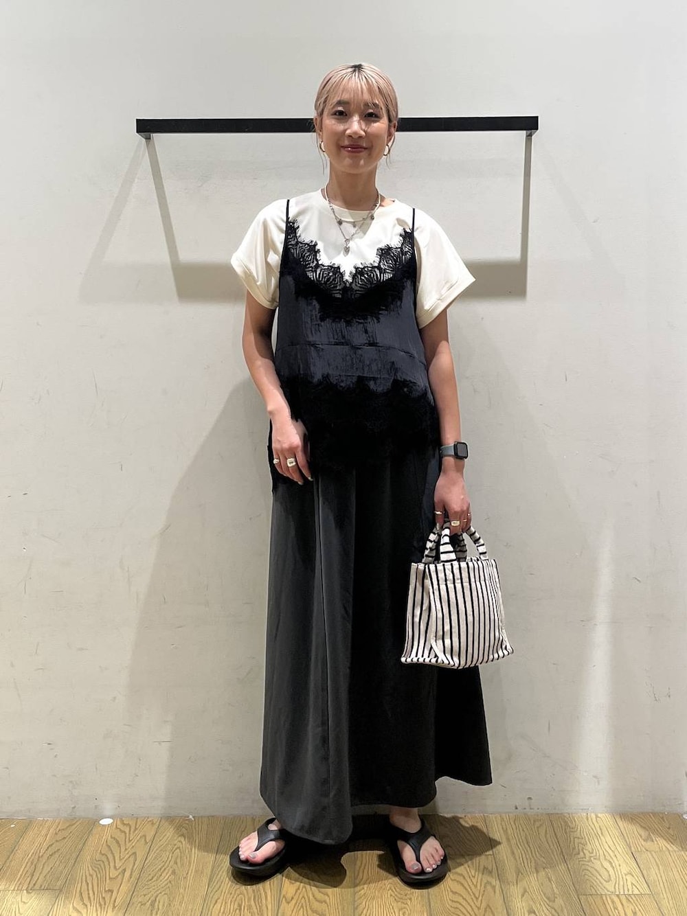 ベージュ系のトートバッグ、グレー系のスカート、ホワイト系のTシャツ/カットソーを着用したレディースの夏コーディネートの1枚目の写真
