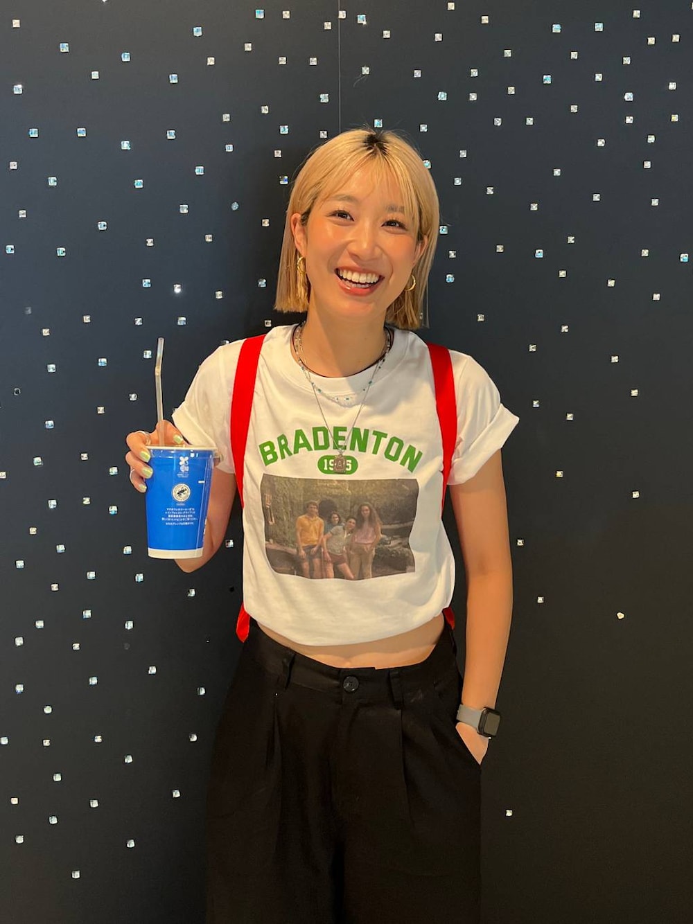 レッド系のバックパック/リュック、ブラック系のチノパンツ、グリーン系のTシャツ/カットソーを着用したレディースの夏コーディネートの1枚目の写真