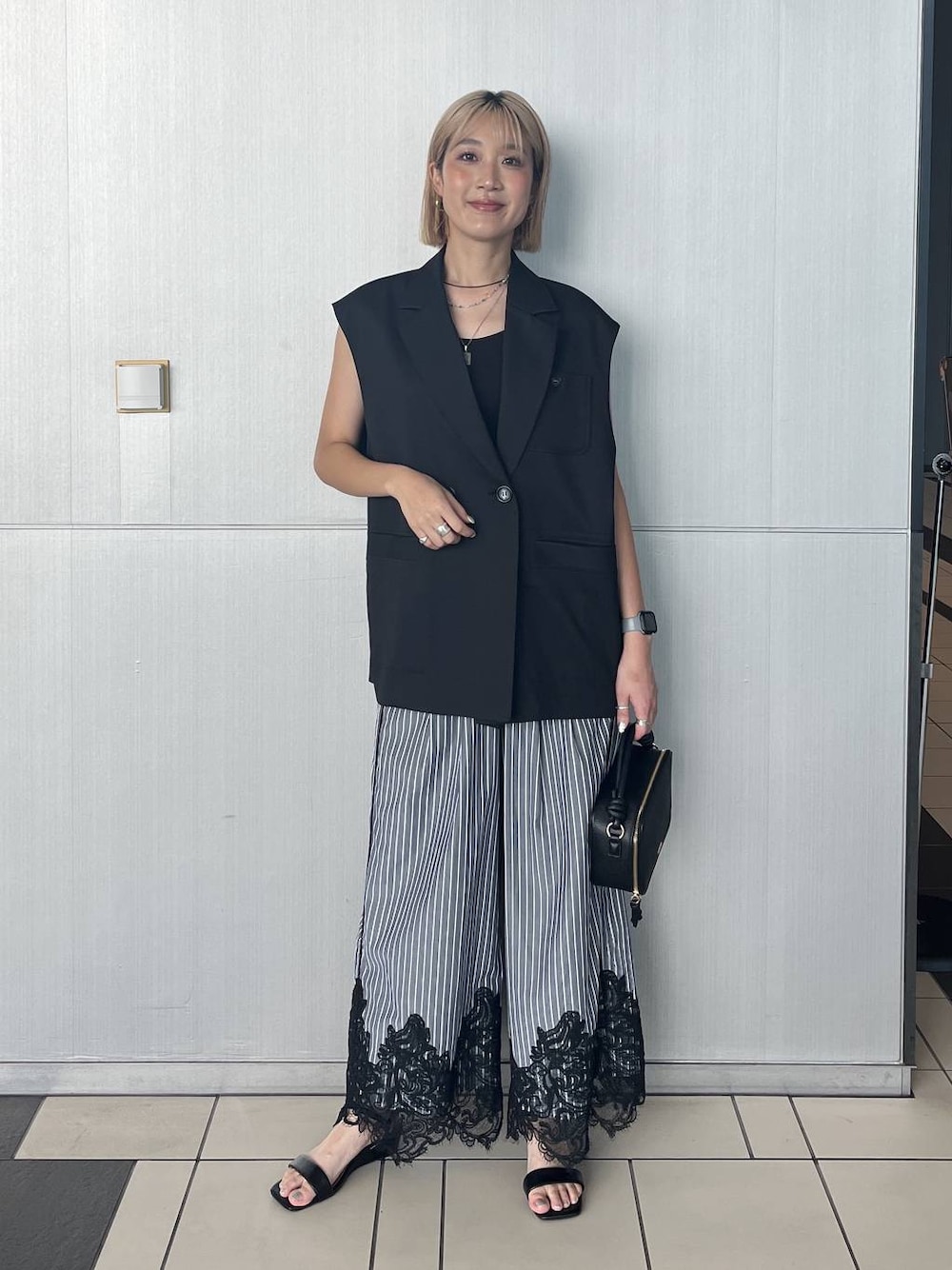 ブラック系のサンダル、ブラック系のベストを着用したレディースの夏コーディネートの1枚目の写真