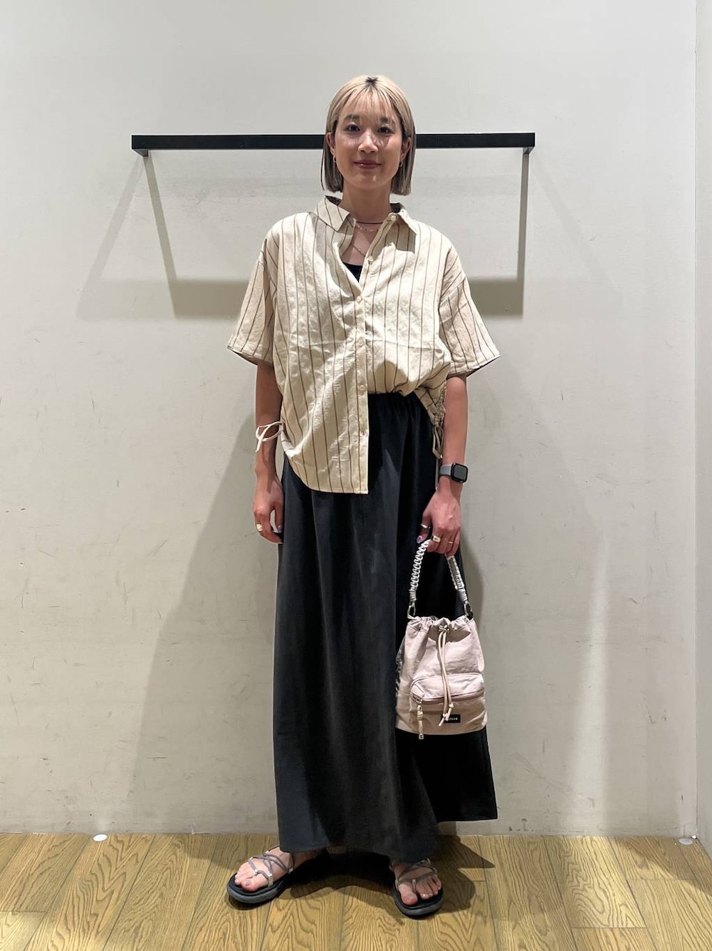 ベージュ系のショルダーバッグ、ベージュ系のシャツ/ブラウス、グレー系のスカートを着用したレディースの夏コーディネートの1枚目の写真