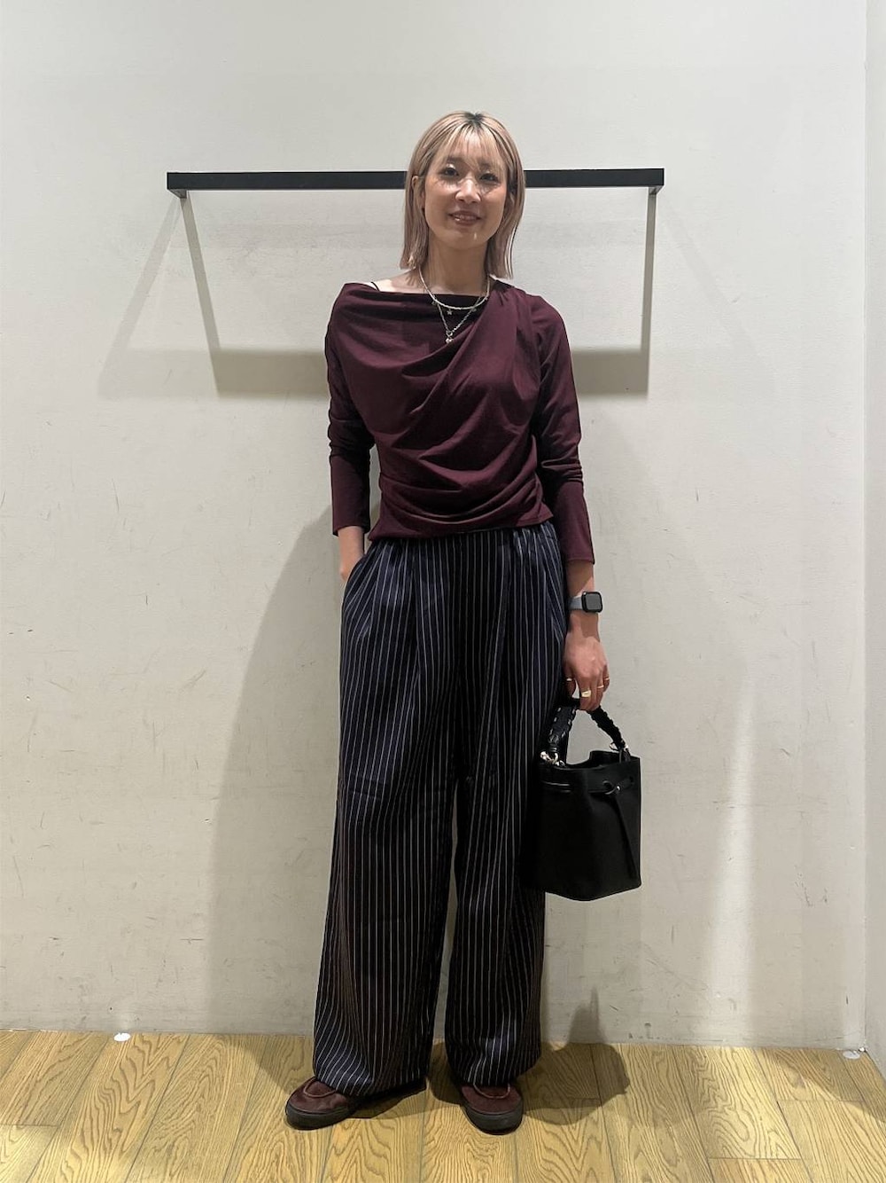 ブルー系のスラックス、レッド系のTシャツ/カットソー、ブラック系のショルダーバッグを着用したレディースの秋コーディネートの1枚目の写真