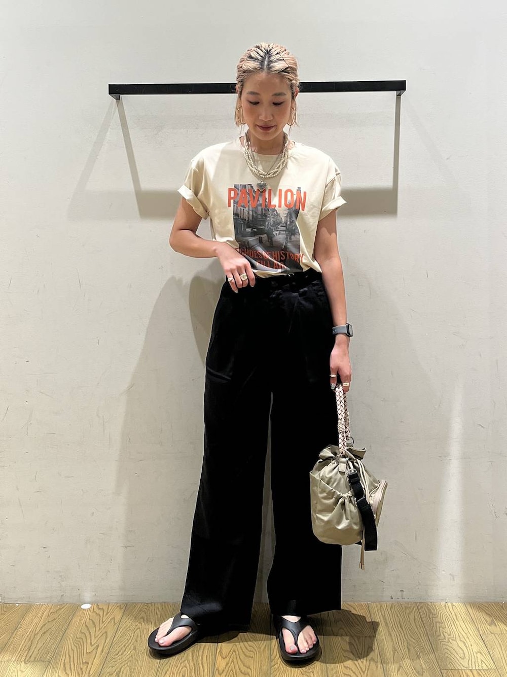 ベージュ系のTシャツ/カットソー、ブラック系のチノパンツ、ベージュ系のショルダーバッグを着用したレディースの夏コーディネートの1枚目の写真
