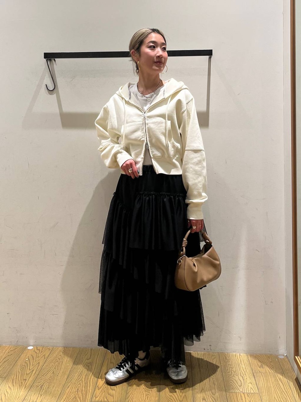 ベージュ系のハンドバッグ、ブラック系のスカート、ベージュ系のパーカーを着用したレディースの春コーディネートの1枚目の写真