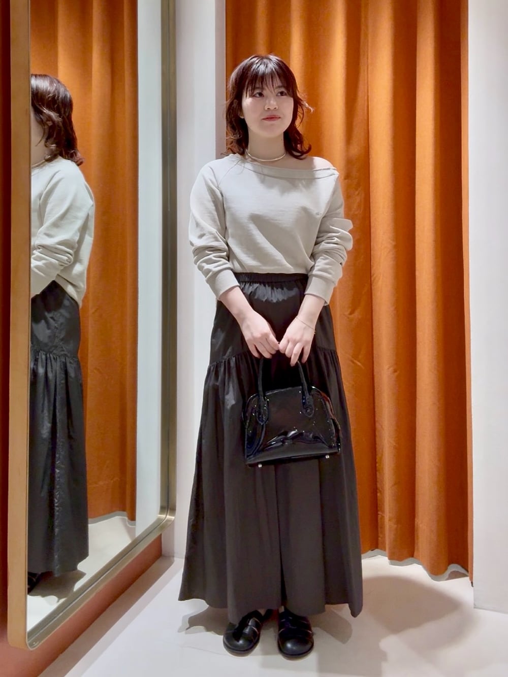 ブラウン系のスカート、ブラック系のボストンバッグ、ベージュ系のスウェットを着用したレディースの春コーディネートの1枚目の写真