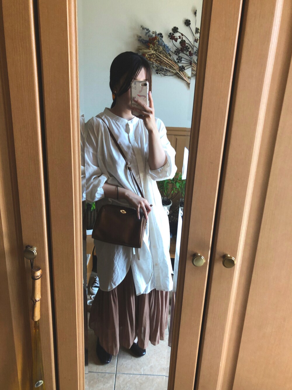 ブラウン系のショルダーバッグ、ブラウン系のスカート、ホワイト系のシャツ/ブラウスを着用したレディースの秋コーディネートの1枚目の写真