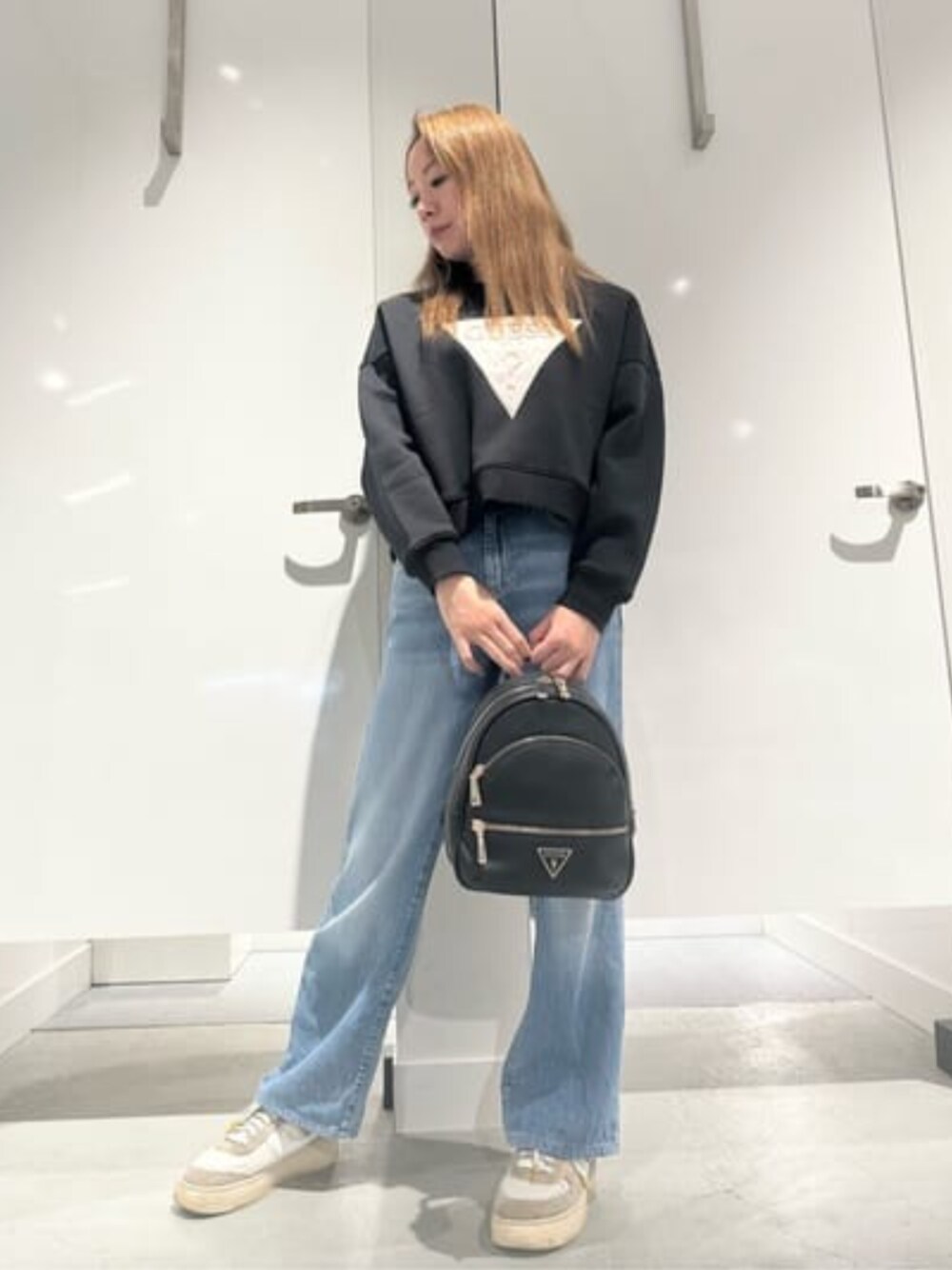 ブラック系のバックパック/リュック、ブルー系のデニムパンツ、ブラック系のスウェットを着用したレディースの春コーディネートの1枚目の写真