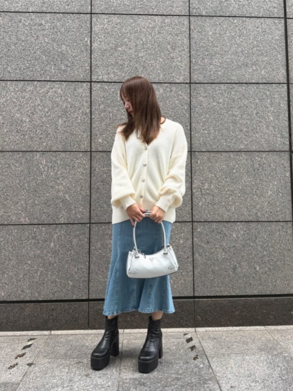 ブルー系のデニムスカート、シルバー系のショルダーバッグ、ベージュ系のカーディガン/ボレロを着用したレディースの秋コーディネートの1枚目の写真