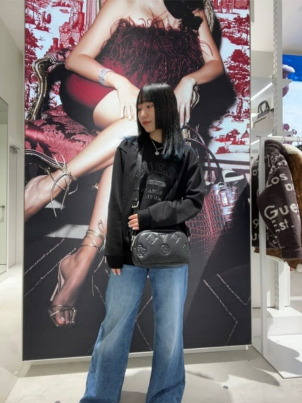 ブルー系のデニムパンツ、ブラック系のショルダーバッグ、ブラック系のスウェットを着用したレディースの秋コーディネートの1枚目の写真