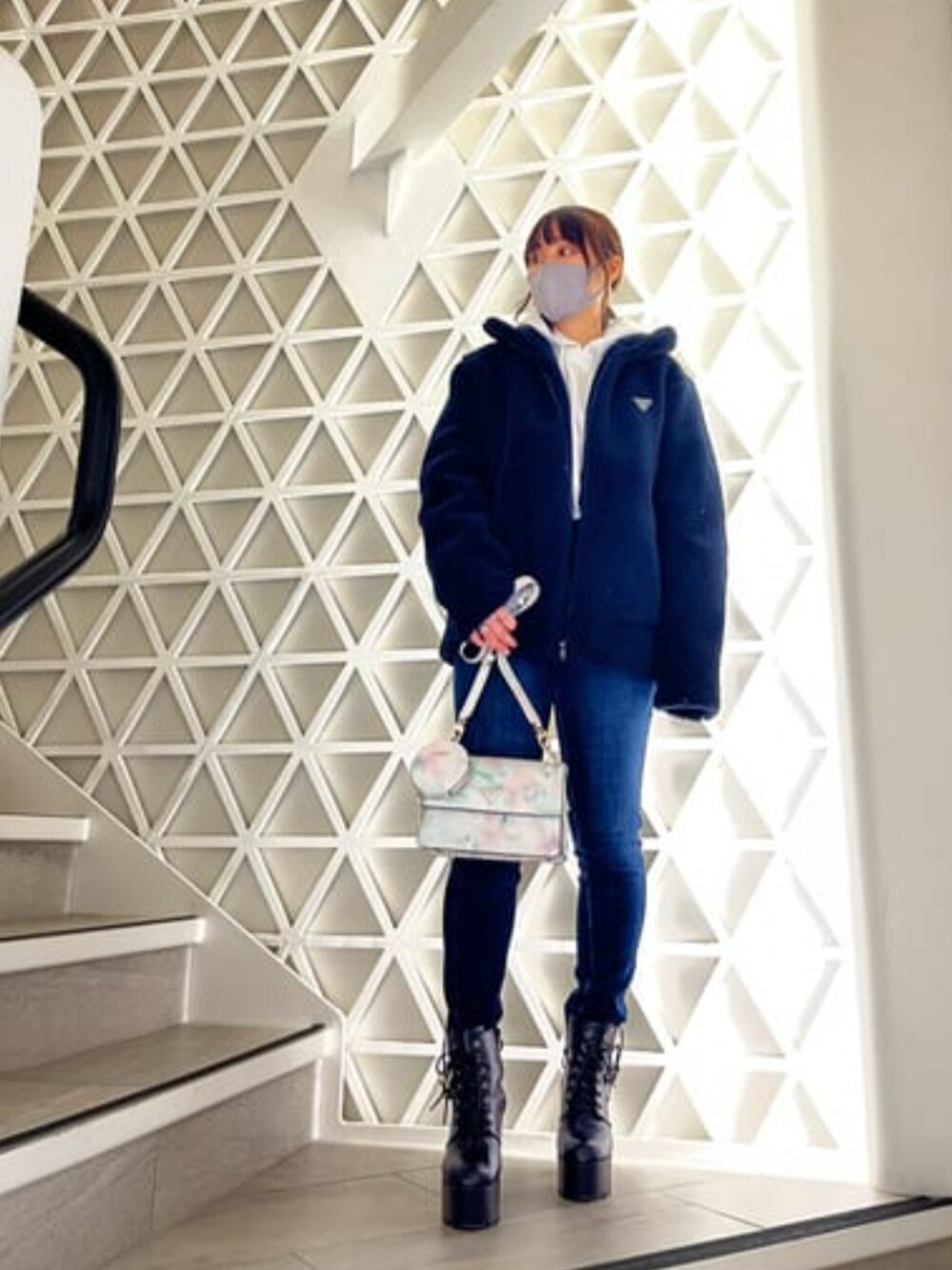 ブルー系のブルゾン、ホワイト系のパーカー、ブルー系のデニムパンツを着用したレディースの冬コーディネートの1枚目の写真